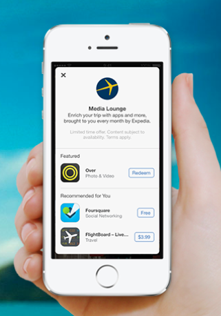 A hand holding a smartphone displaying the Media Lounge app interface with featured apps and recommendations. The background shows a blurred blue sky.