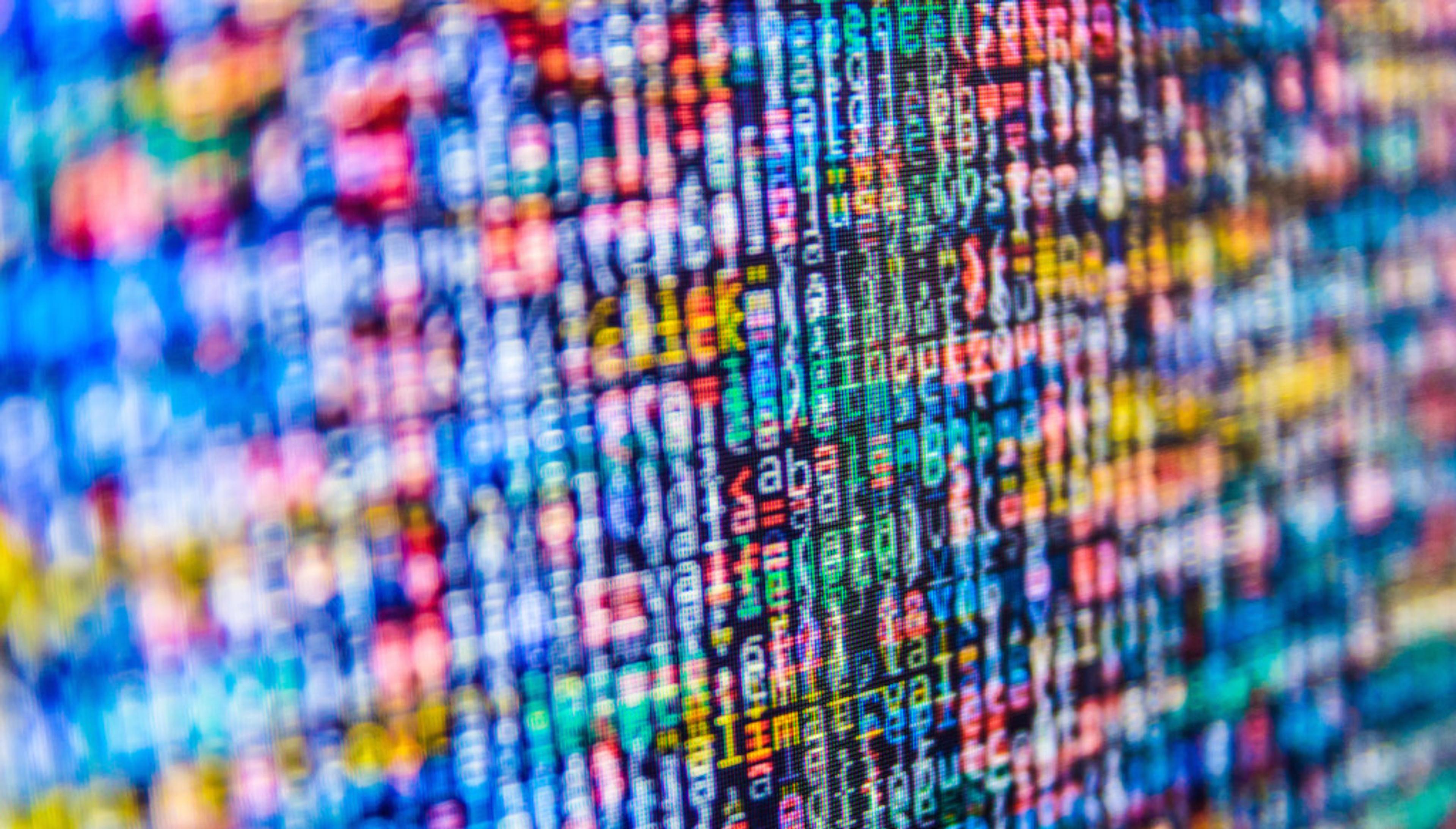 A close-up of colorful, abstract digital code displayed on a screen, featuring a mix of letters and numbers. The image has a blurred effect, emphasizing the vibrant colors.