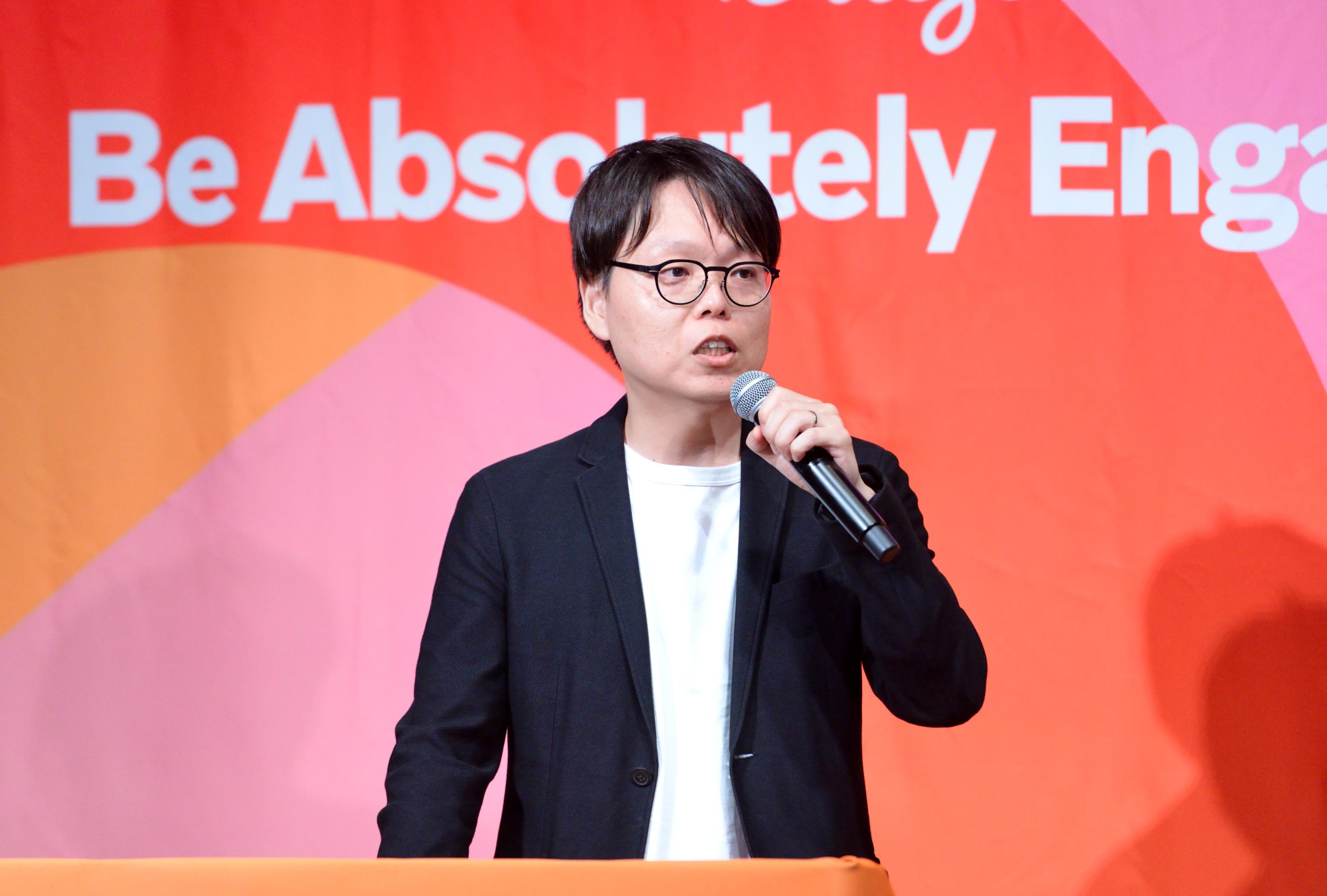 a man in a suit and glasses is standing at a podium holding a microphone .