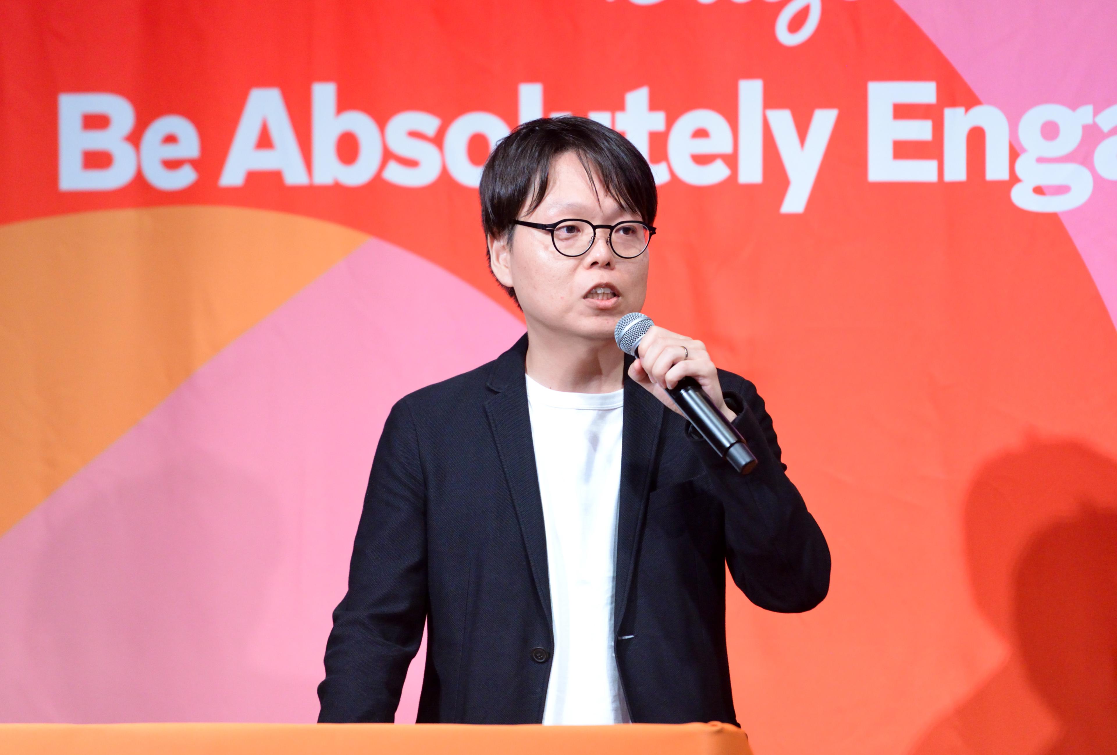 a man in a suit and glasses is standing at a podium holding a microphone .