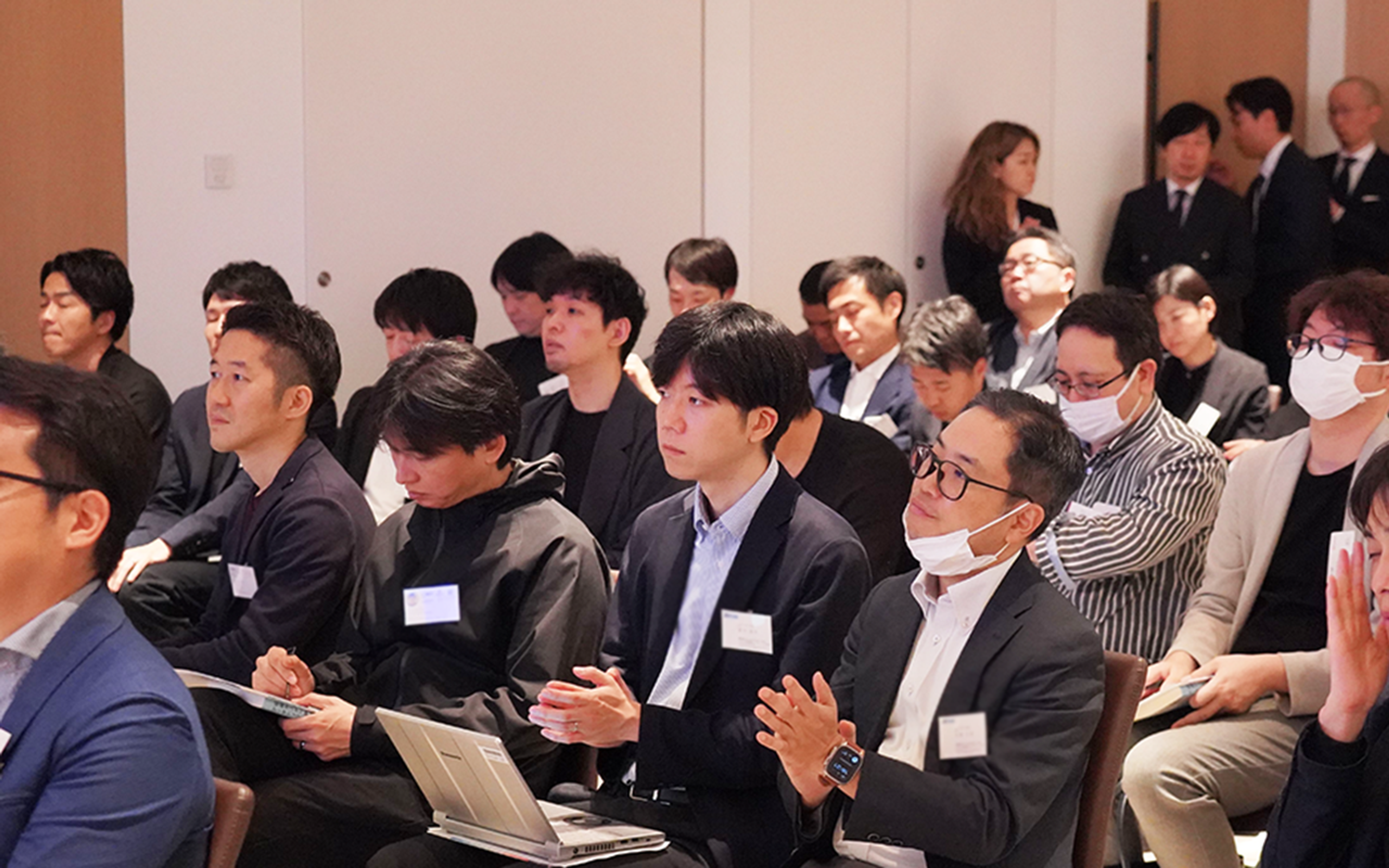 参加者が座っている会議室の様子。数人が拍手をしている。