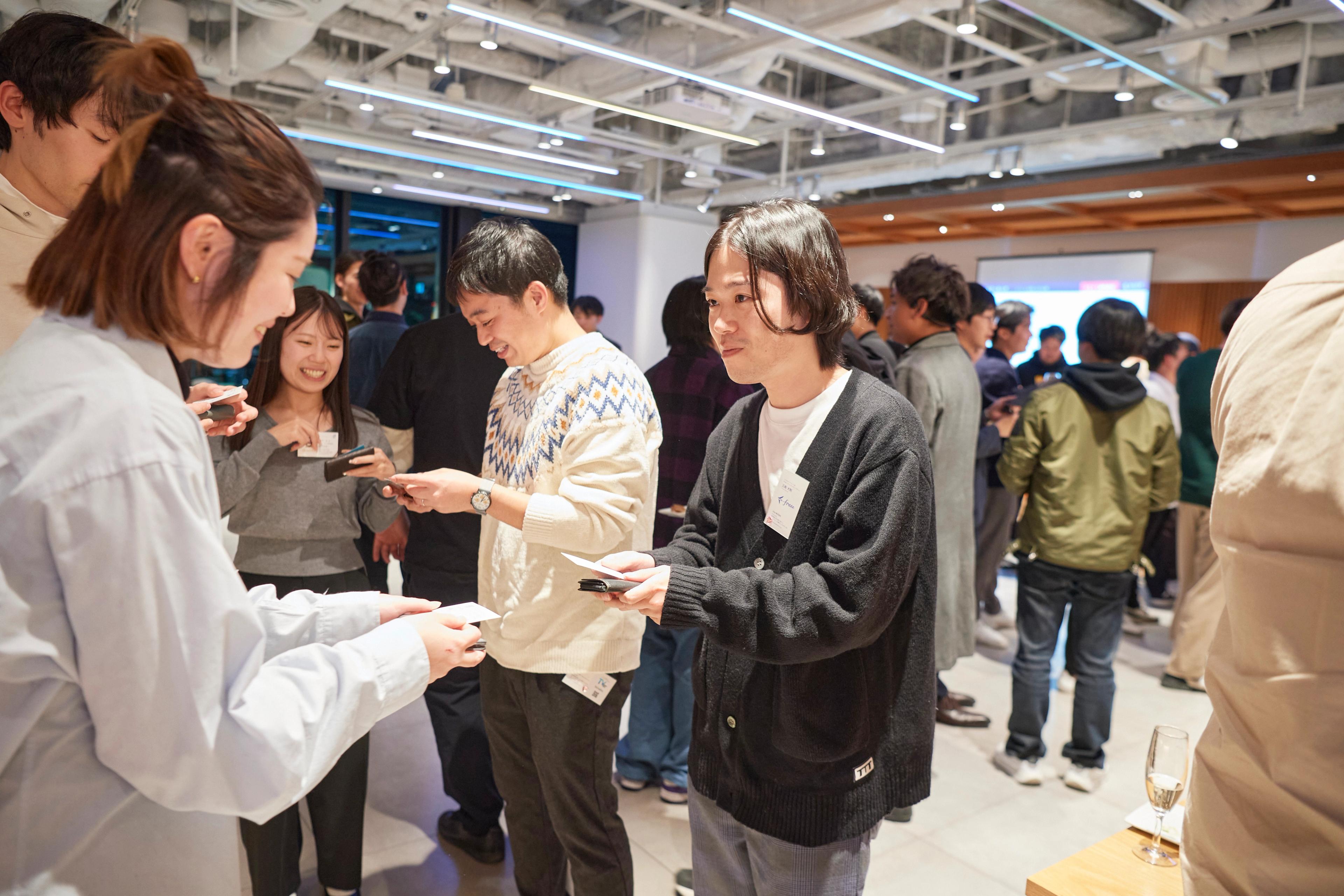 a group of people are standing in a room talking to each other .