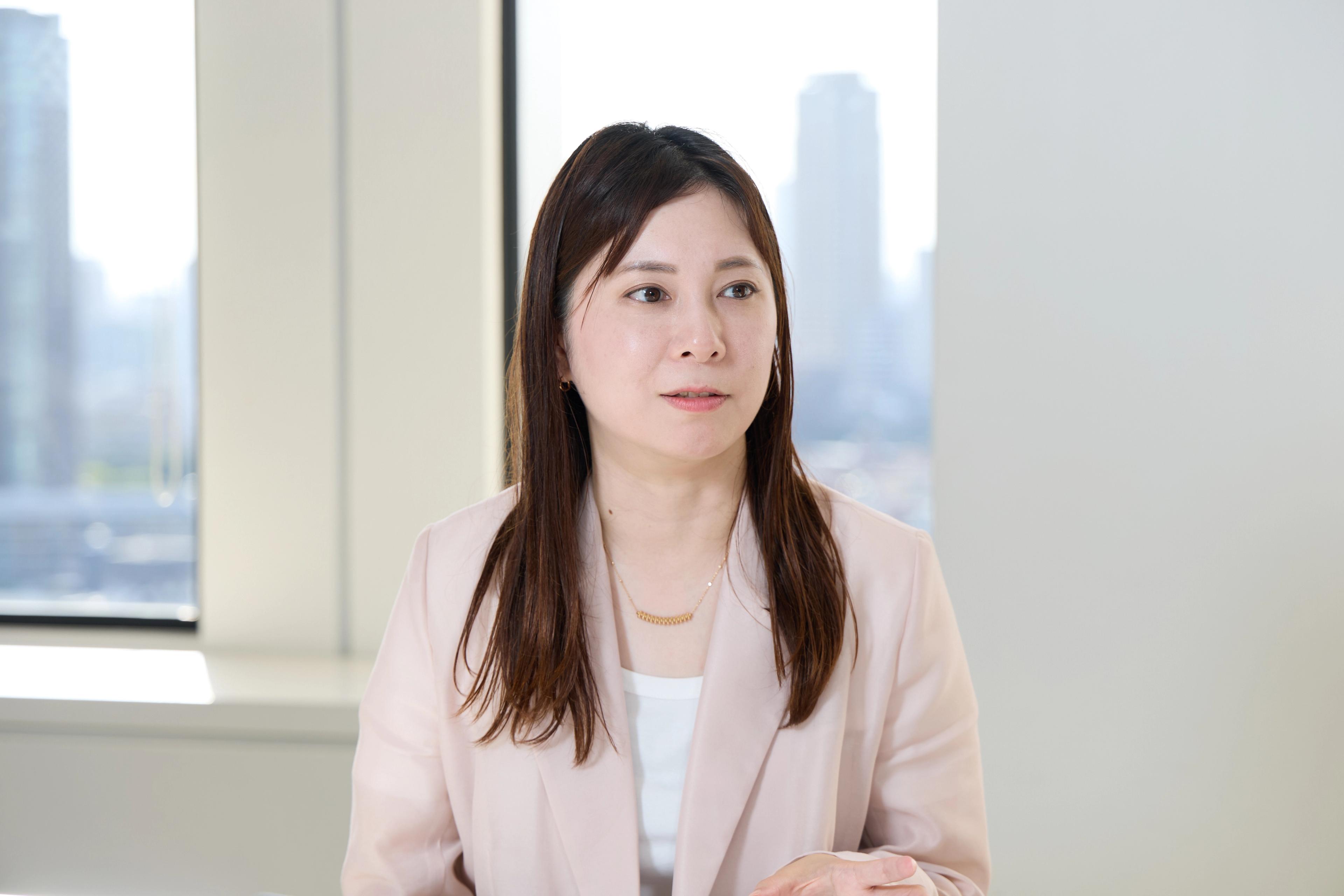 マーケティング部 リレーション推進グループ マネジャー 田中 空見子氏がインタビューに答える様子。ピンクのジャケットに白いシャツを着ている