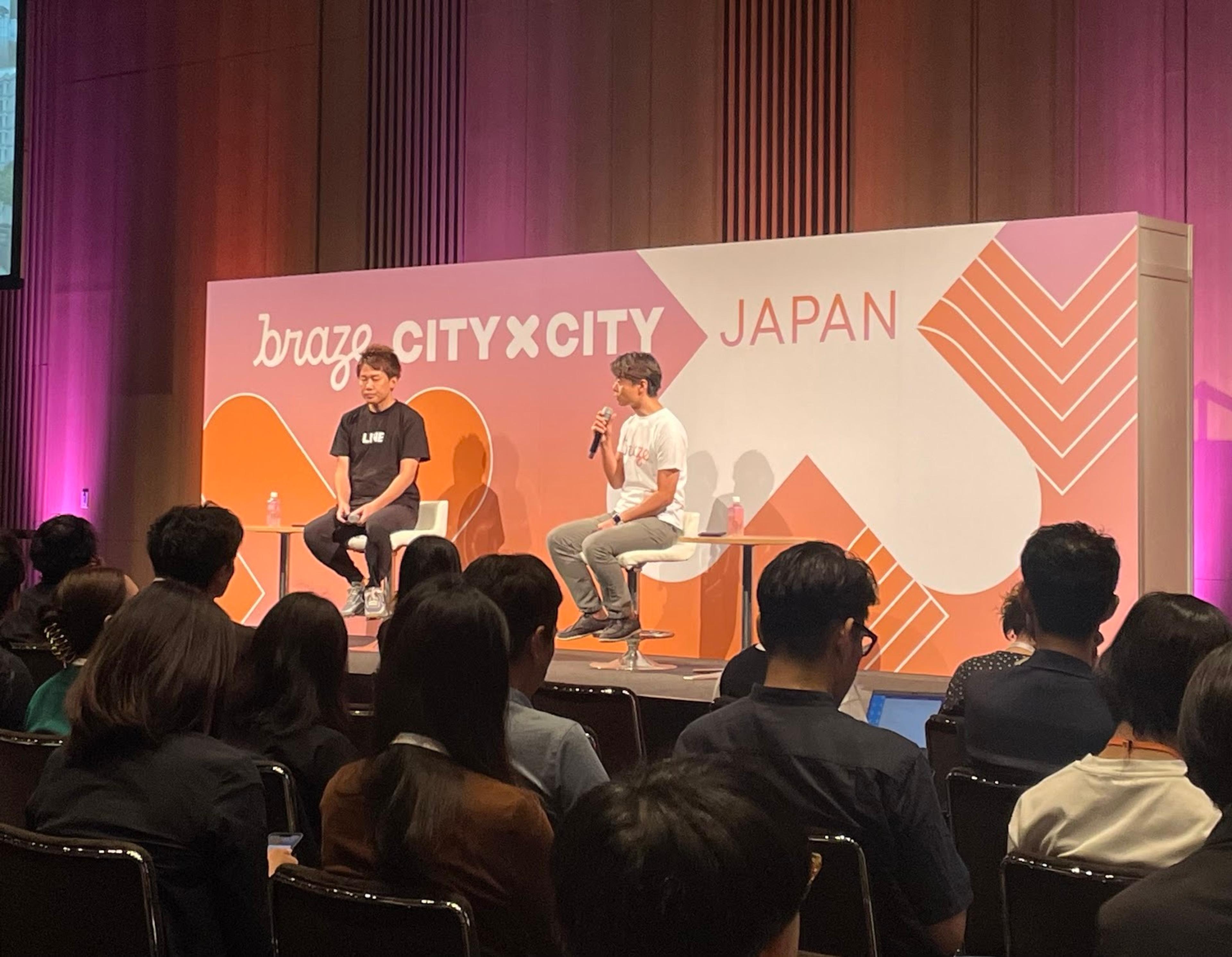 ブレイズのイベントで、二人のスピーカーがステージで話しています。観客が座って聞いています。