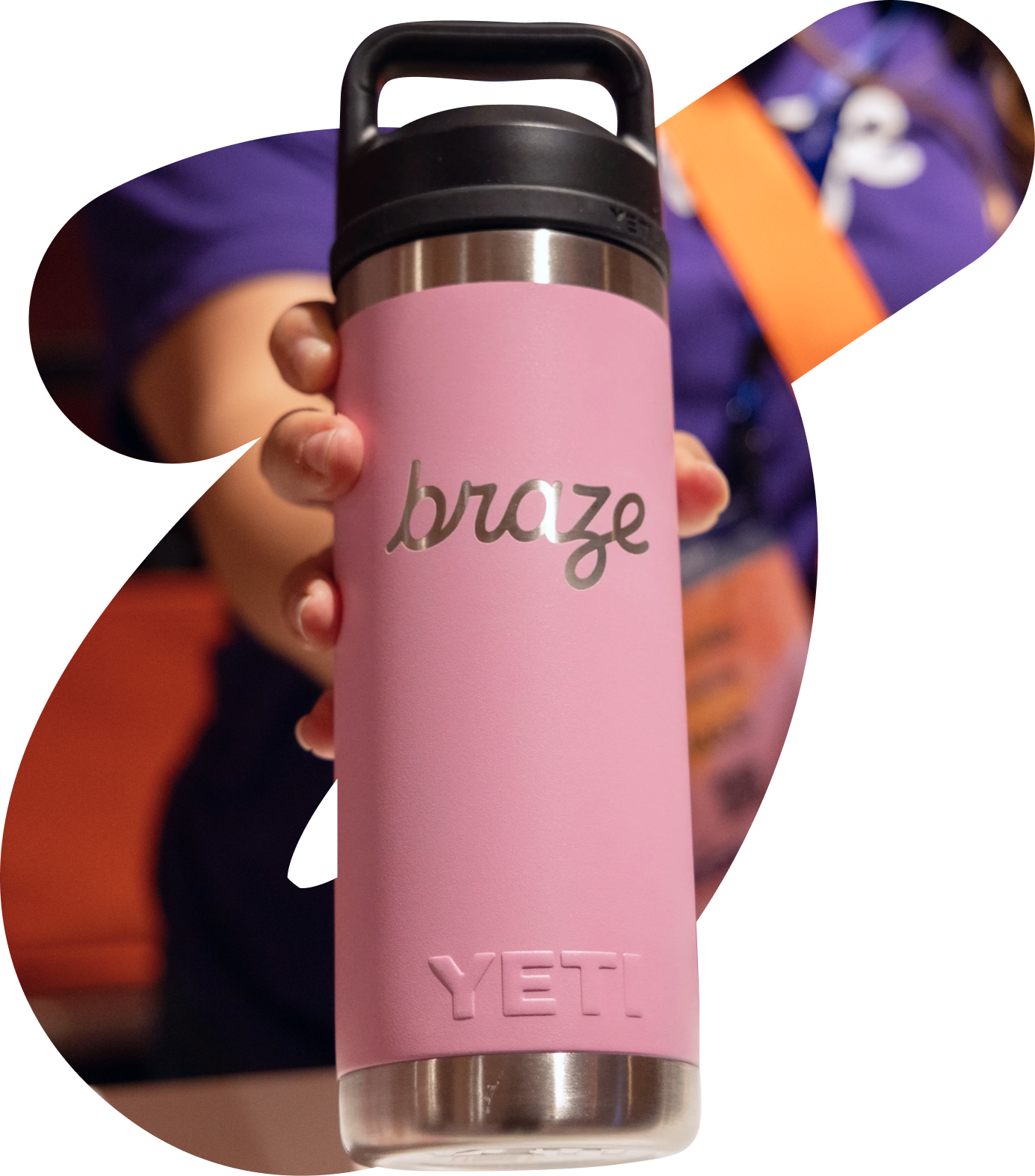 A hand holds a pink YETI water bottle customized with the "braze" logo.