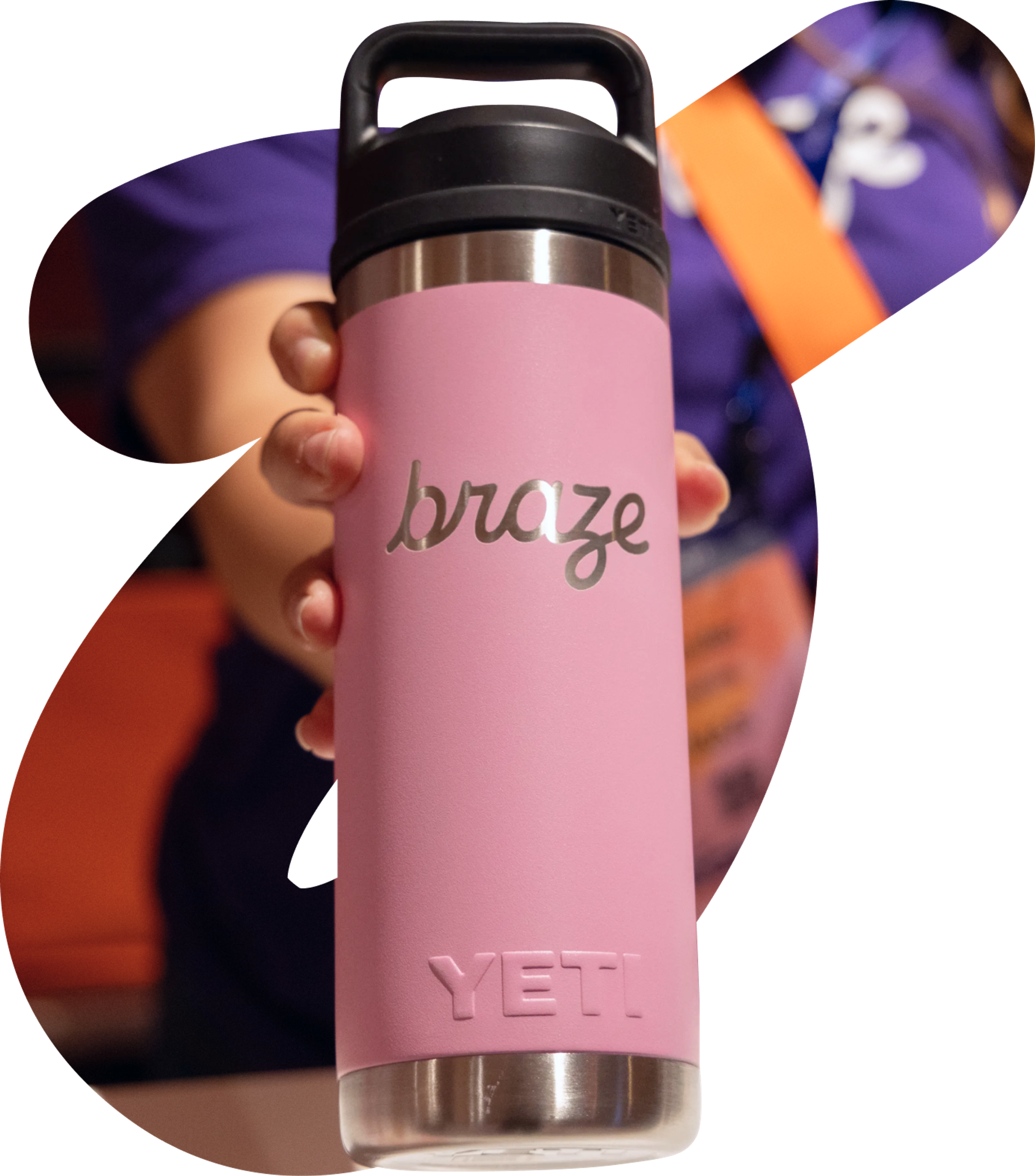 A hand holds a pink YETI water bottle customized with the "braze" logo.