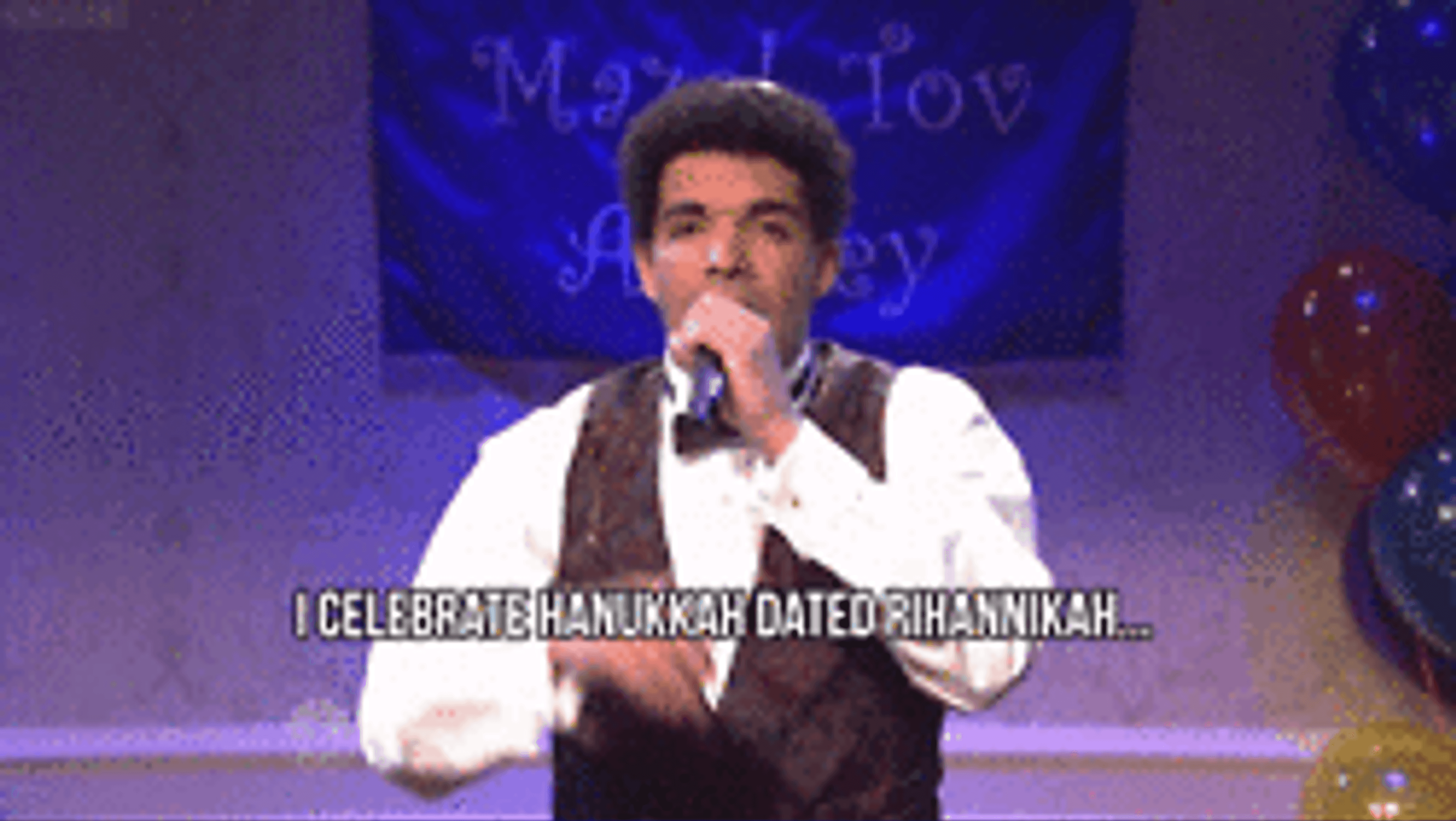 A man in a tuxedo performs on stage, singing about celebrating Hanukkah and dating Rihanna. Colorful balloons and a festive banner are in the background.