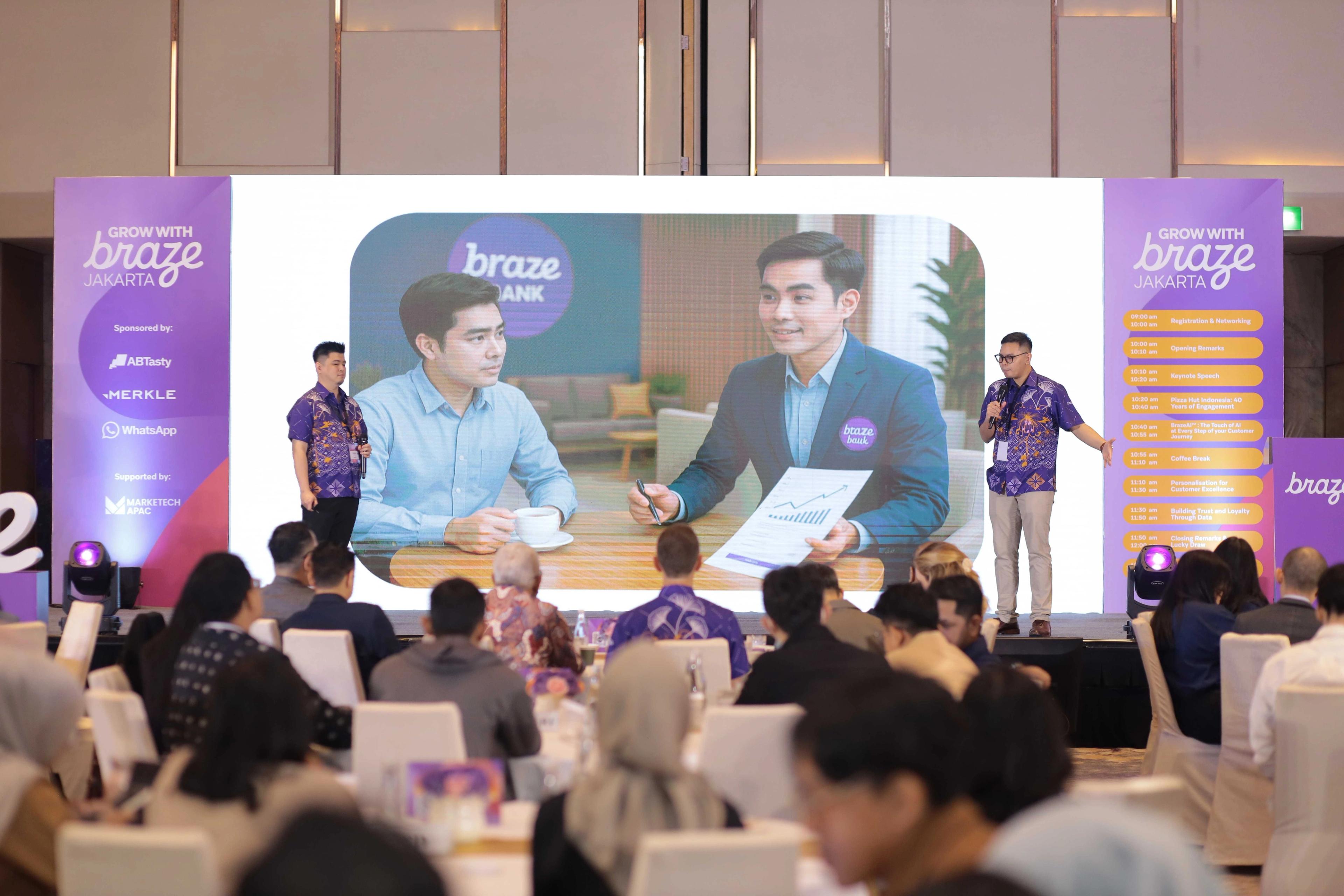a group of people are sitting at tables in front of a large screen .