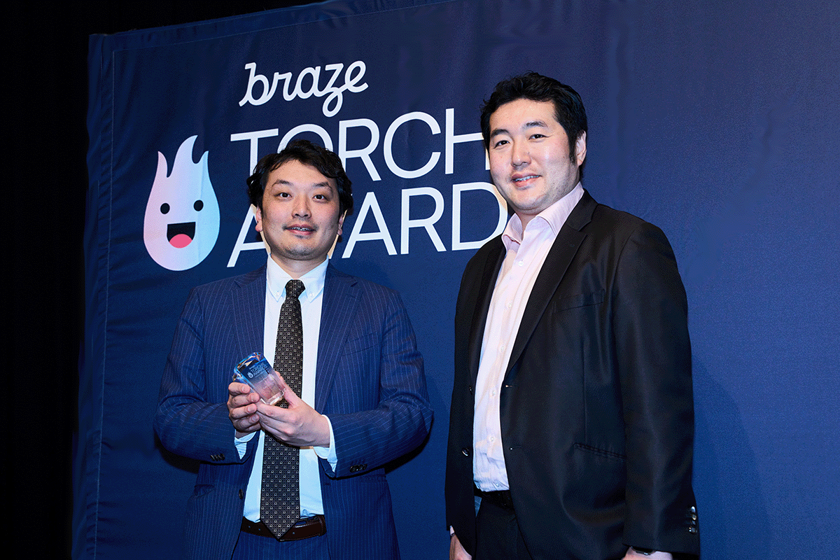 受賞者がトロフィーを持ち、もう一人の男性と一緒にポーズをとっています。背景には「BRAZE TORCH AWARDS」のロゴがあります。