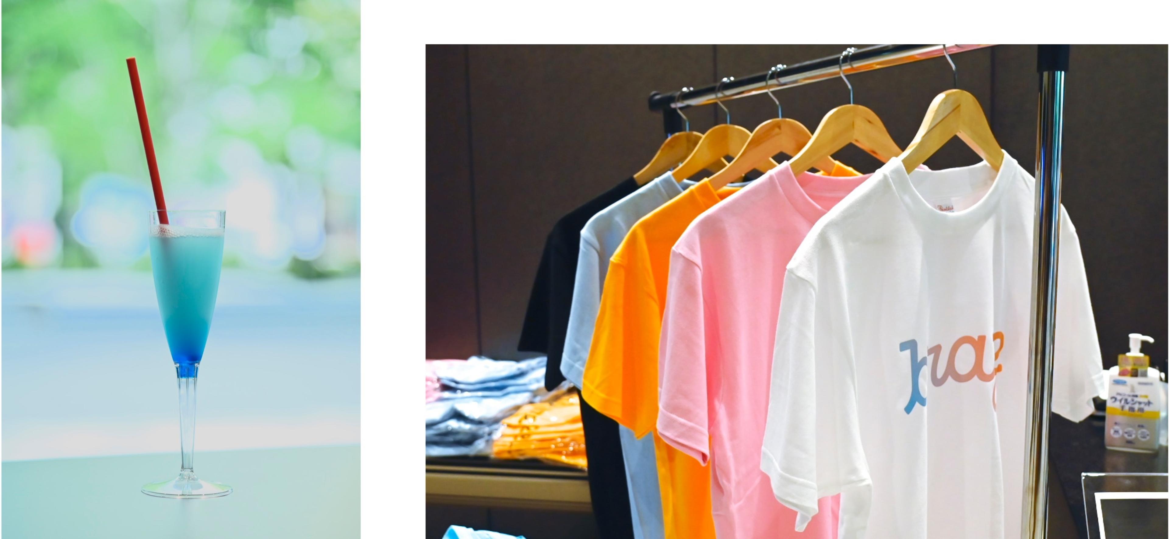 青い飲み物が入ったグラスと、色とりどりのTシャツが掛けられたラック。