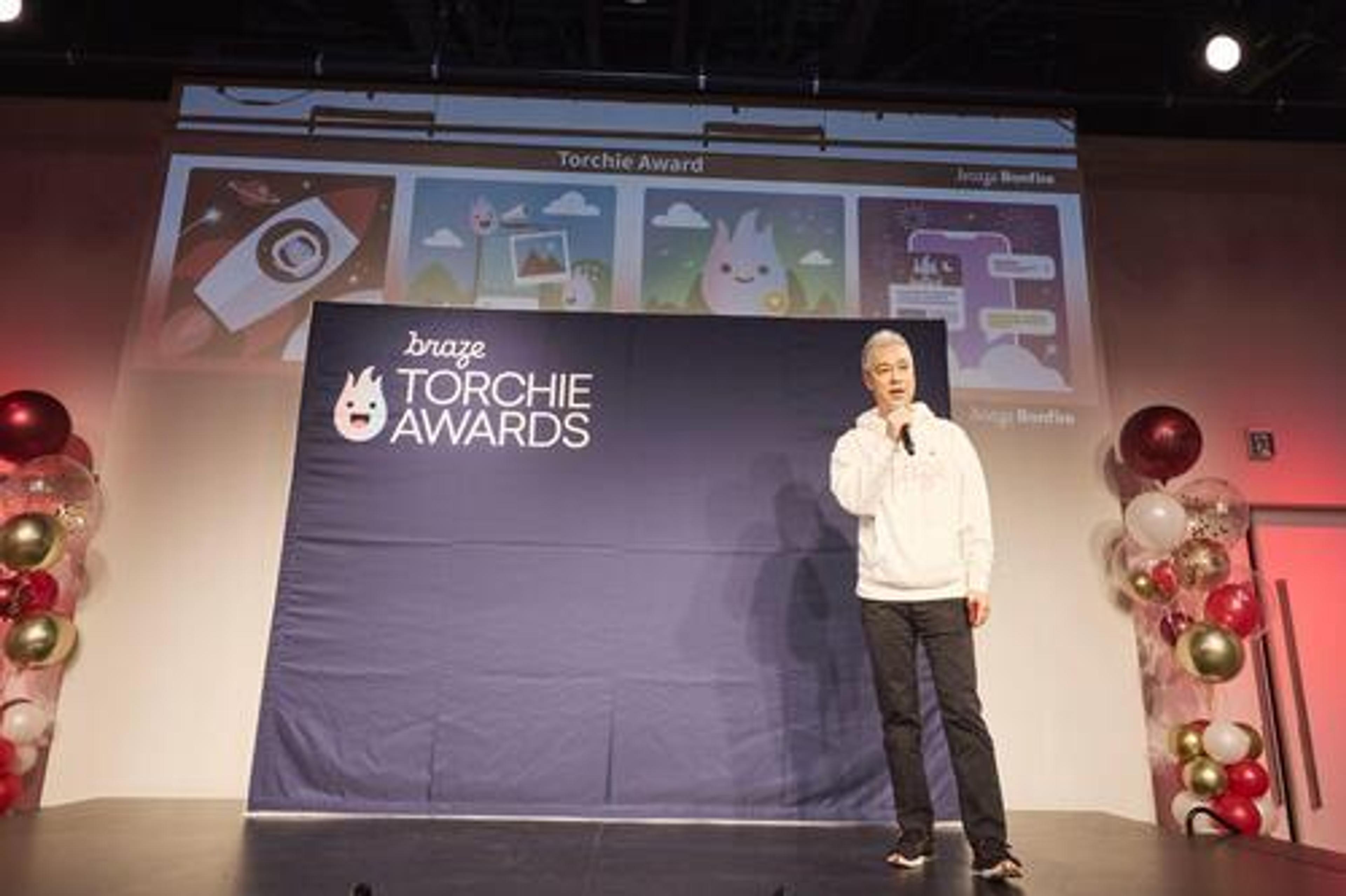 ステージでスピーカーが話している様子。背景には「Torchie Awards」のバナーと装飾が見える。