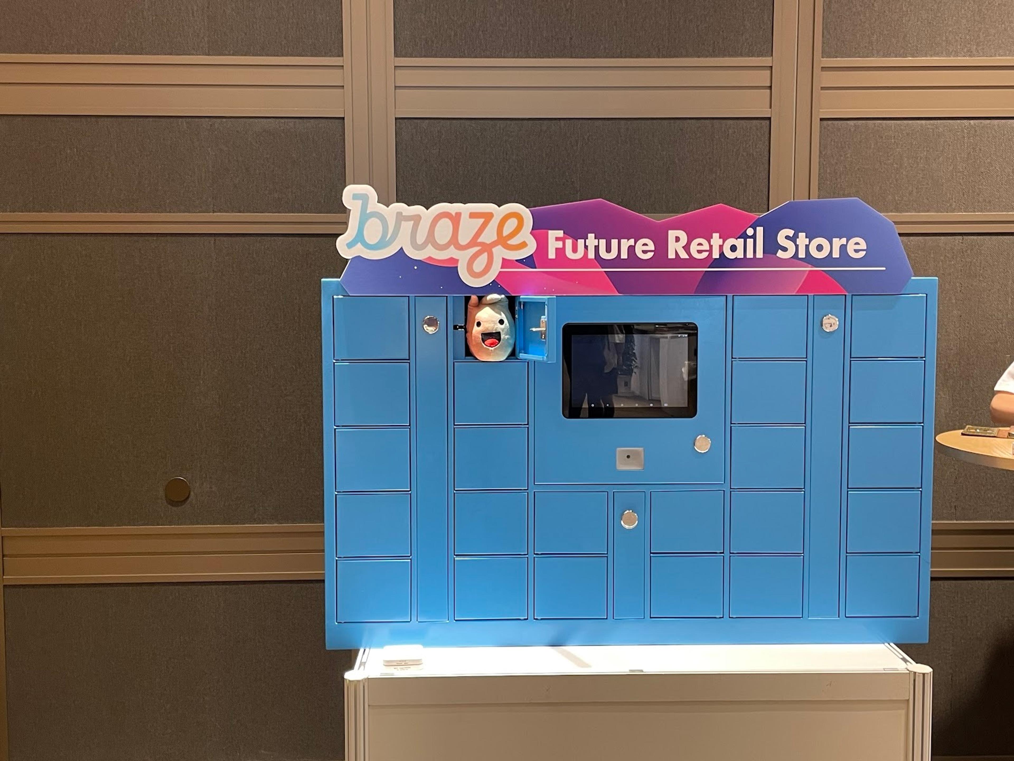 青いロッカーが並んだ「braze Future Retail Store」の展示。ロッカーの一つにはマスコットキャラクターが見える。