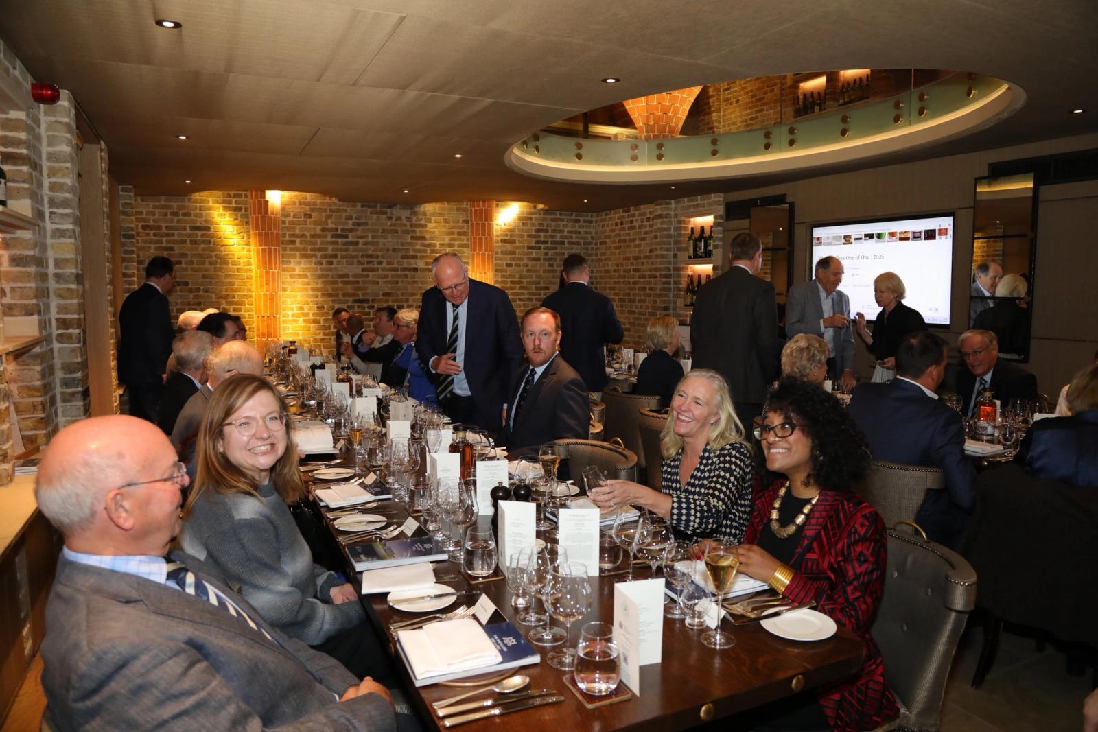 Members talking over dinner at a relaxed gathering in a brick-walled restaurant.