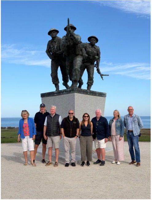 The group beneath the bronze sculpture of three soldiers at the British Normandy Memorial