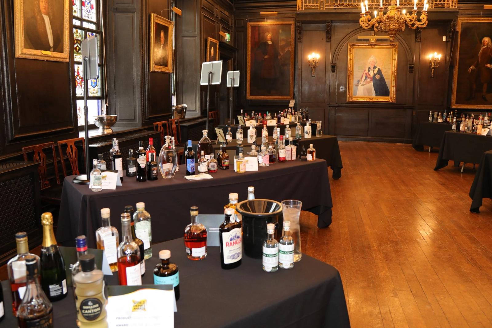Tables of spirits laid out for a tasting in a wood-panelled livery hall.