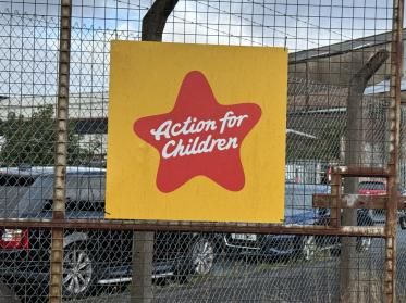 An Action for Children sign fixed to a chain-link fence