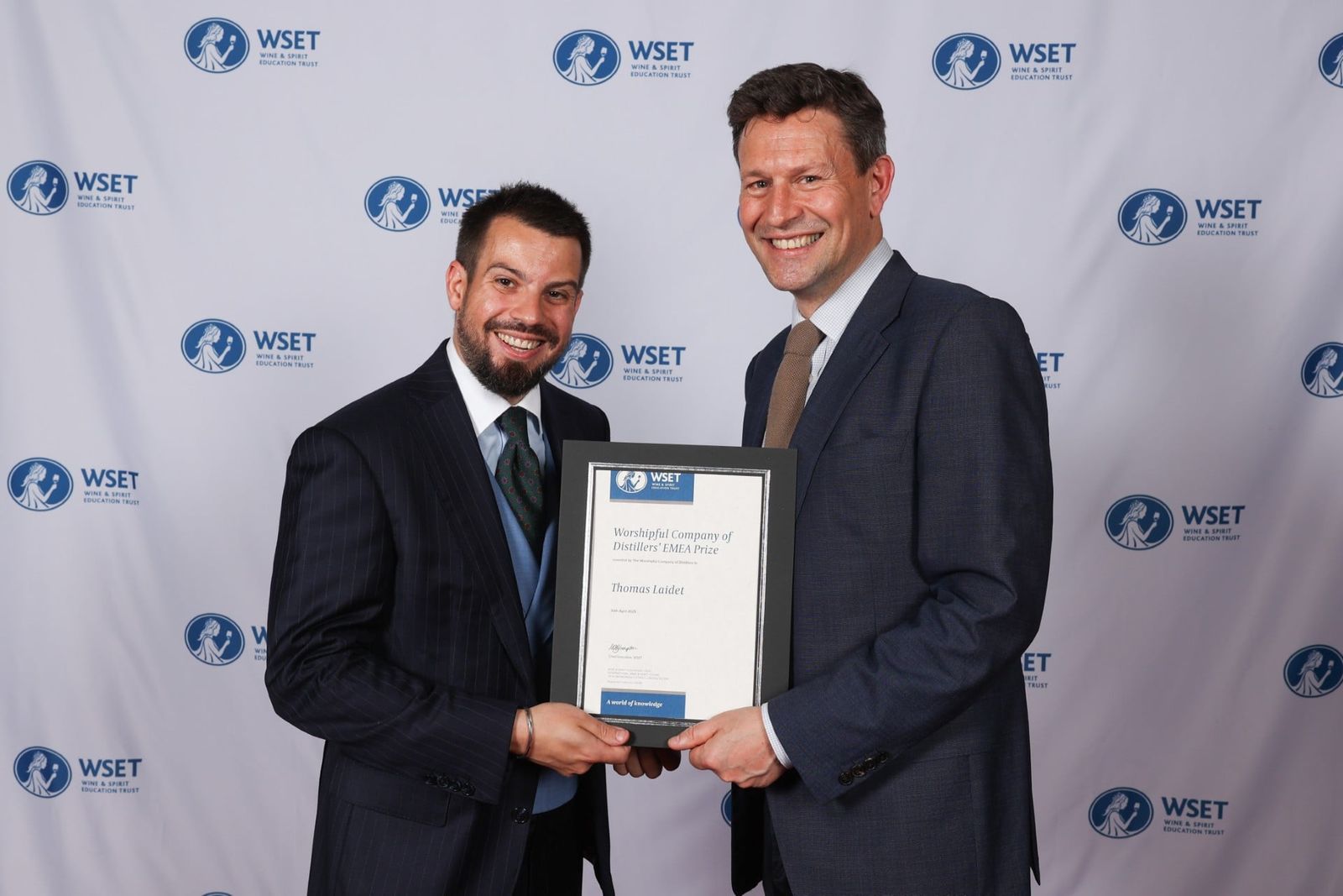 A student receiving a framed Distillers’ Company award certificate at a WSET presentation.