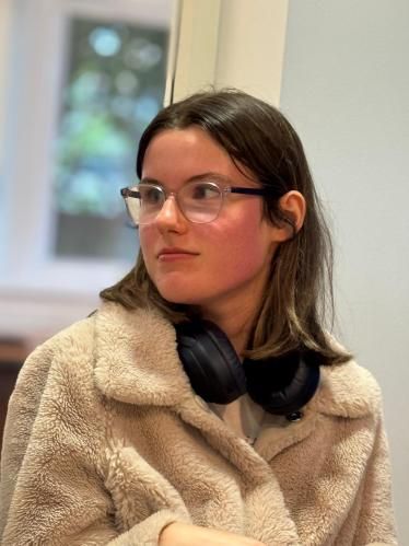 A young woman in a fleece jacket, with headphones around her neck, during the Aberdeen Foyer visit