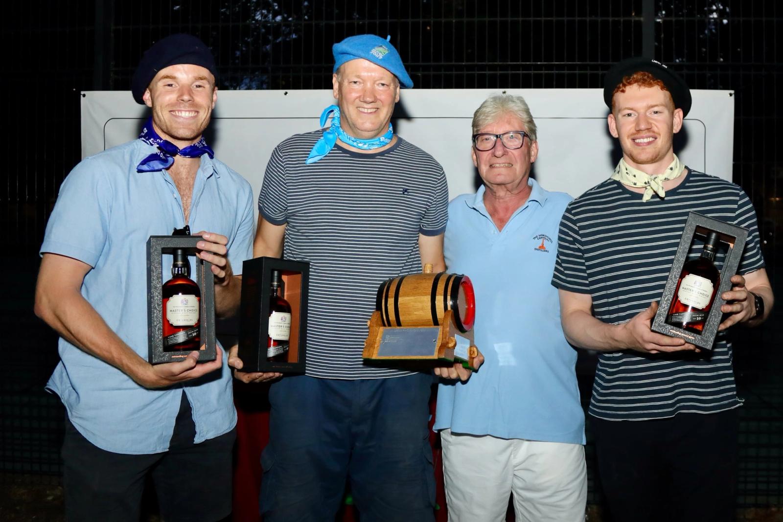 Four members holding whisky prizes and a small cask trophy at a club event.
