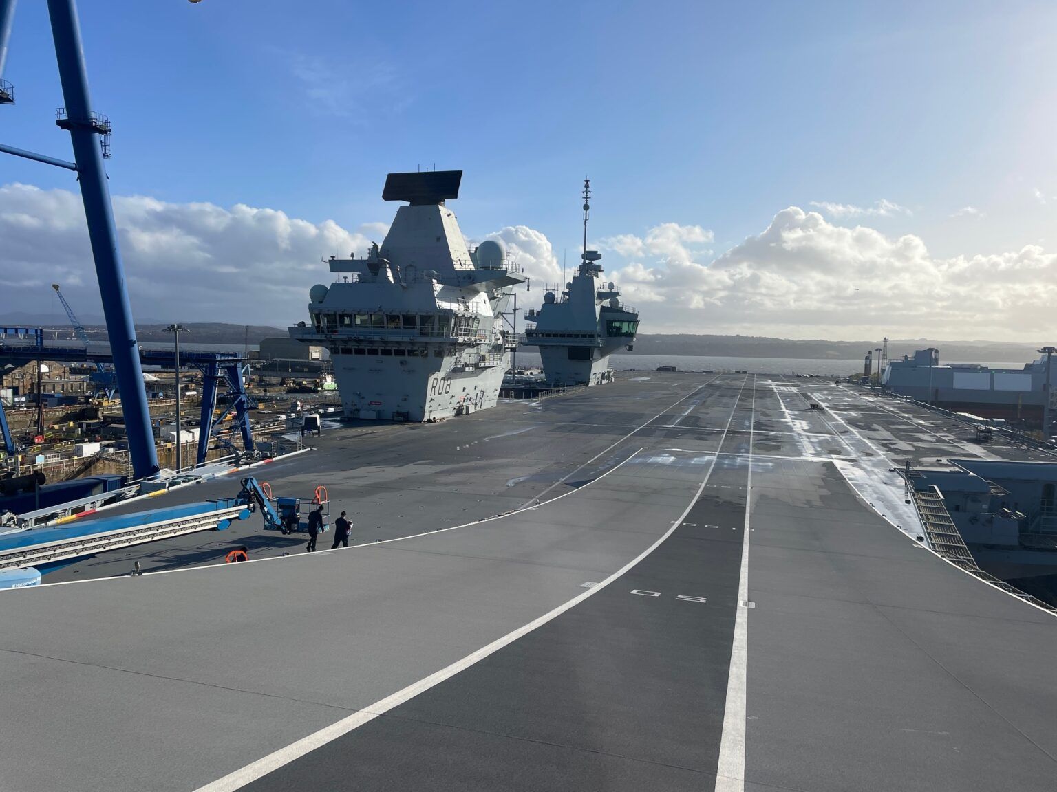 The flight deck of HMS Queen Elizabeth (R08) at Rosyth, with a destroyer alongside