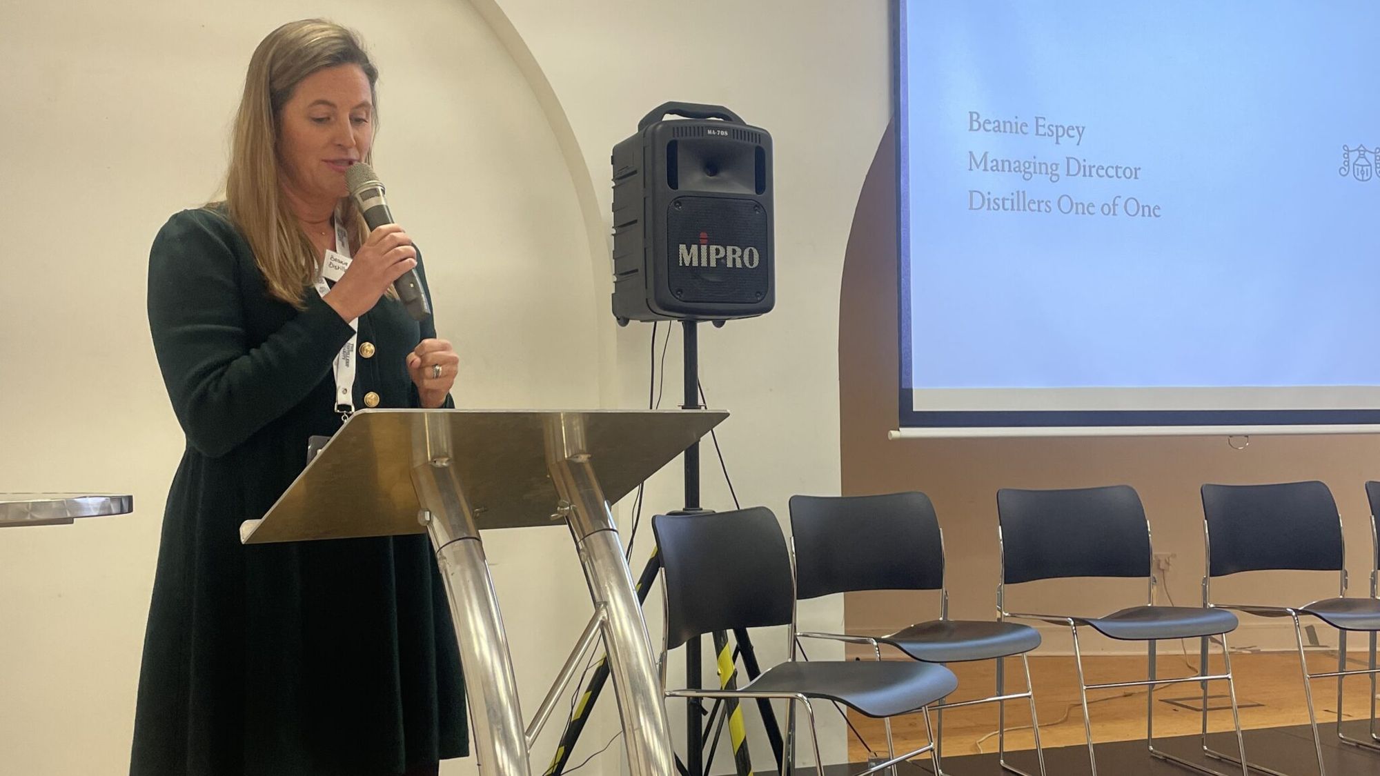 Beanie Espey speaking, with a slide naming her Managing Director of Distillers One of One