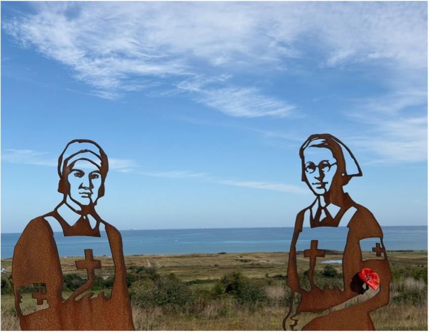 Steel silhouettes of two nurses from Standing with Giants, overlooking the sea