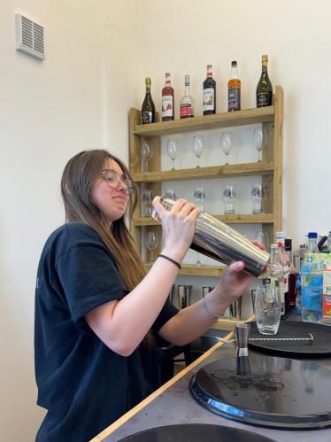 A young woman shaking a cocktail tin at a bar during the Aberdeen Foyer visit