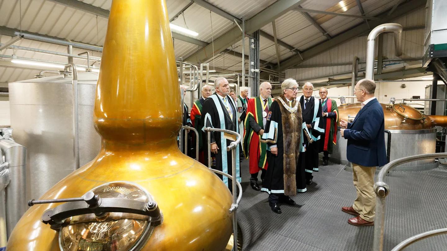 Company members visit copper stills during a distillery inspection.