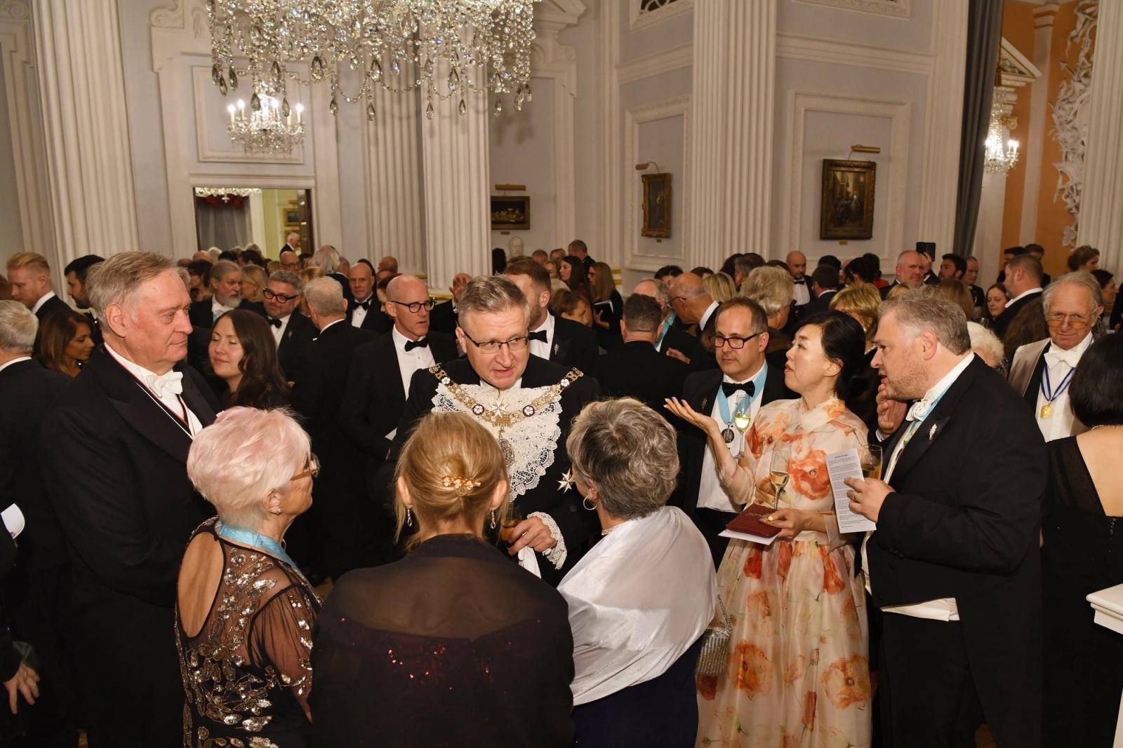Guests in evening dress mingling beneath chandeliers at the Distillers’ 2025 banquet at Mansion House.