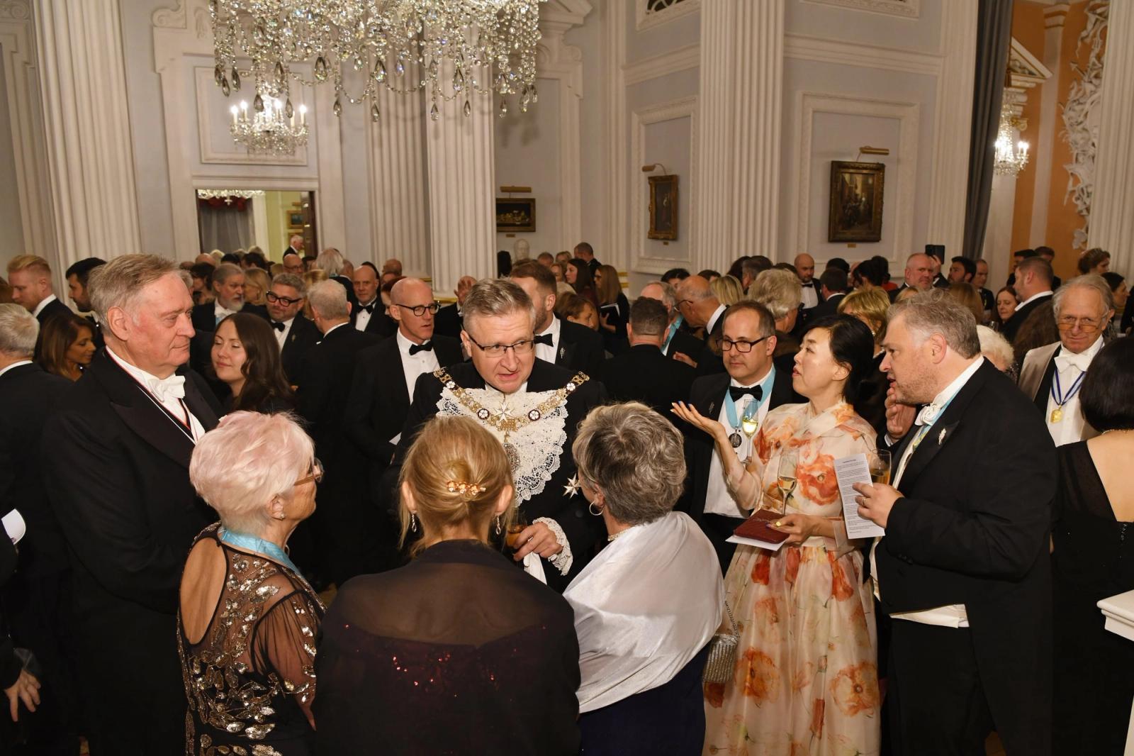 Guests in evening dress mingling beneath chandeliers at the Distillers’ 2025 banquet at Mansion House.