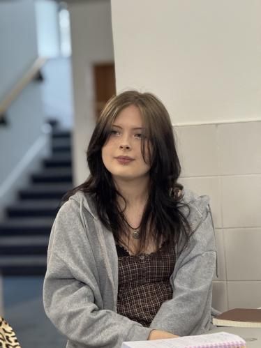 A young woman in a grey hoodie seated at a table during the Aberdeen Foyer visit