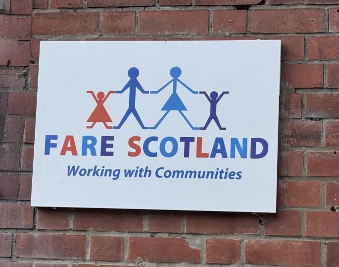 A FARE Scotland sign on a brick wall, reading Working with Communities