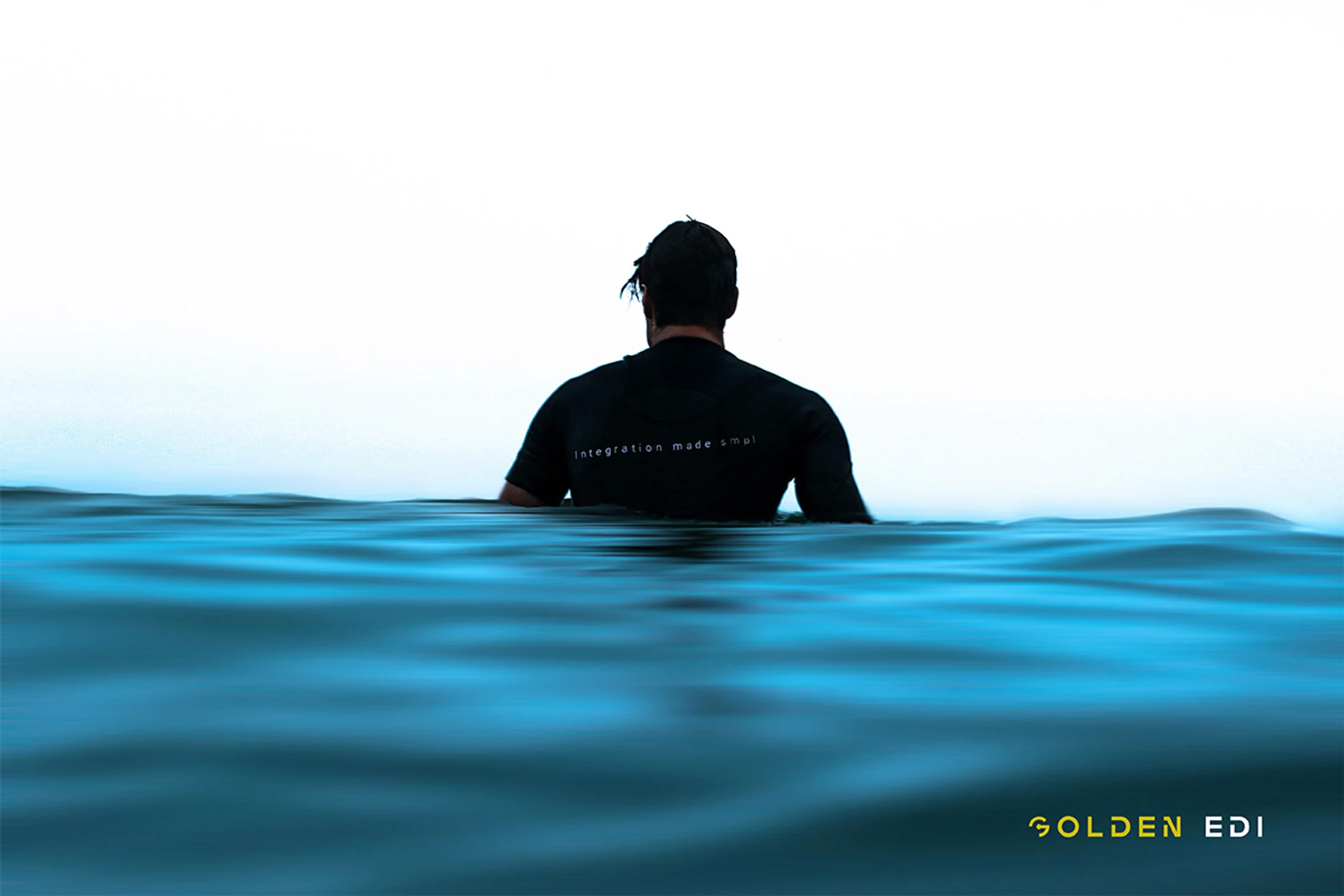 Surfer with Golden EDI t-shirt waiting for wave