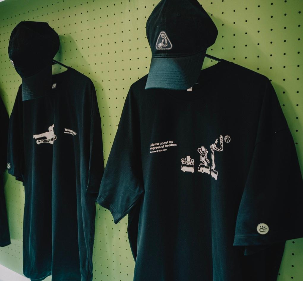 Dexmate T-shirts and caps on a sage green merchandise wall.