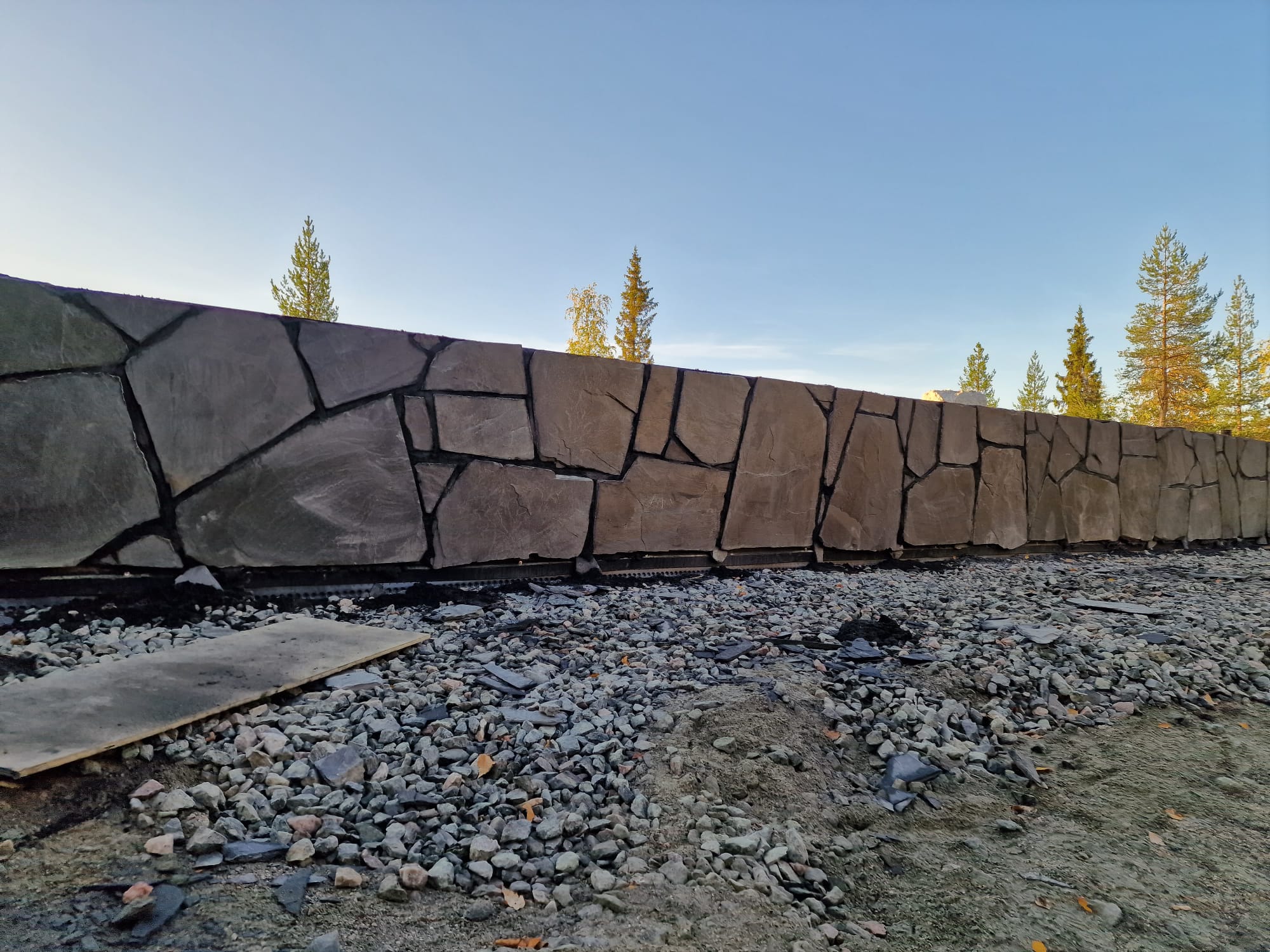 Luonnonkivestä rakennettu tukimuuri tunturirinteen tontilla.