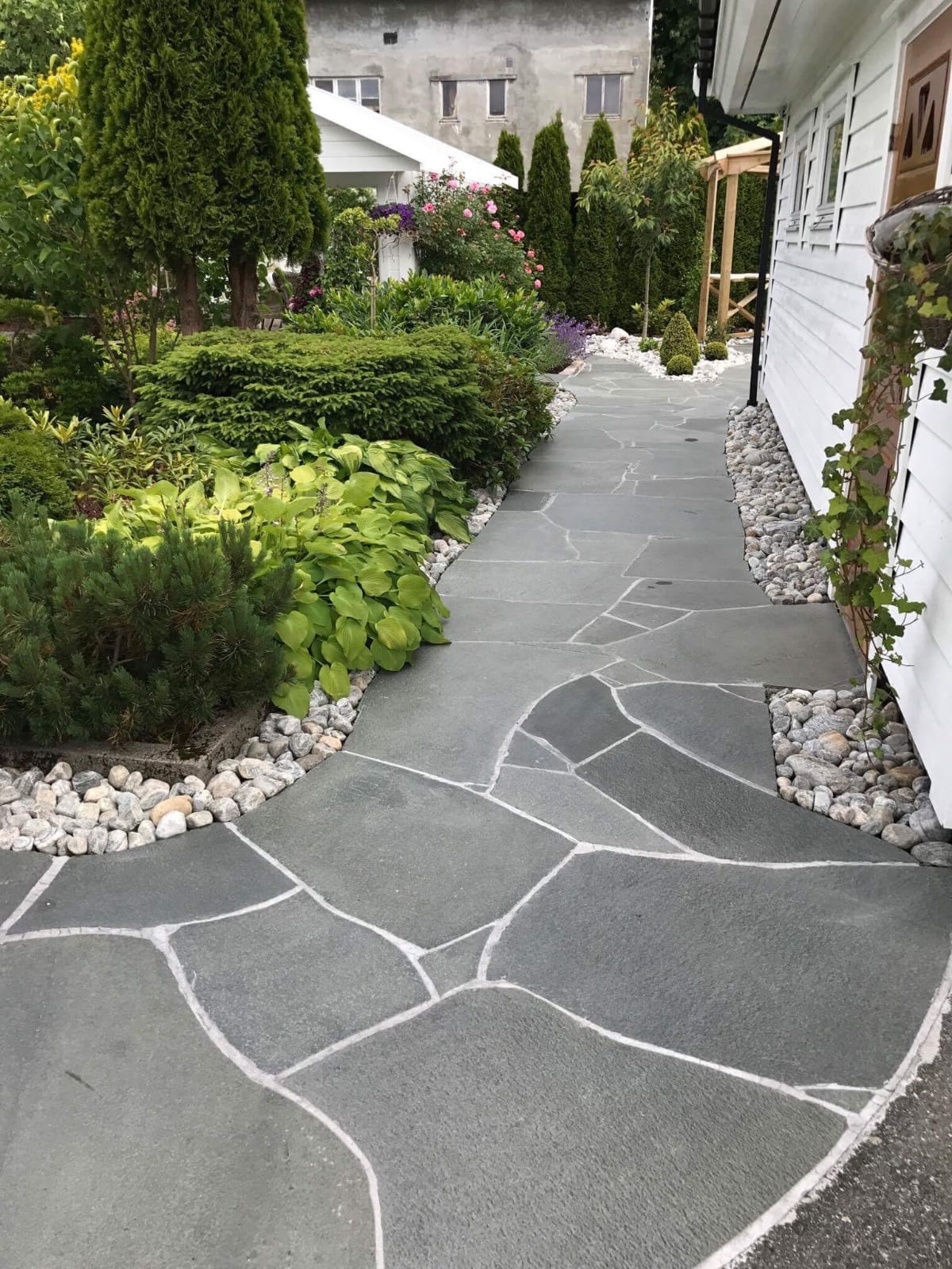 Omakotitalon piha luonnonkivilaatasta.