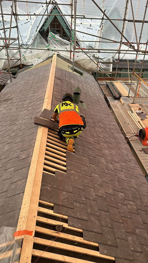 Kansallismuseon katon harjalla liuskekiven asentaja.