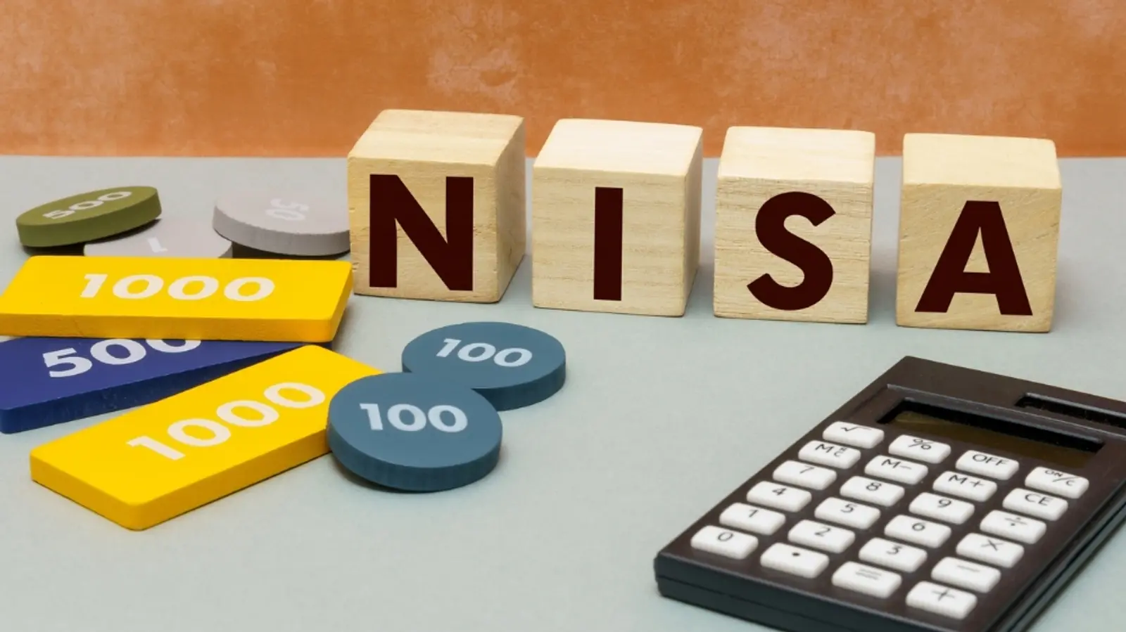 NISA と書かれた木製のブロック、番号付きトークン、および計算機。