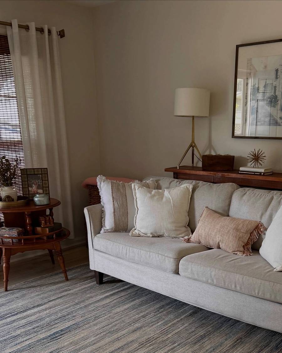 Living room with a cream sofa, layered pillows, art and warm lamp light