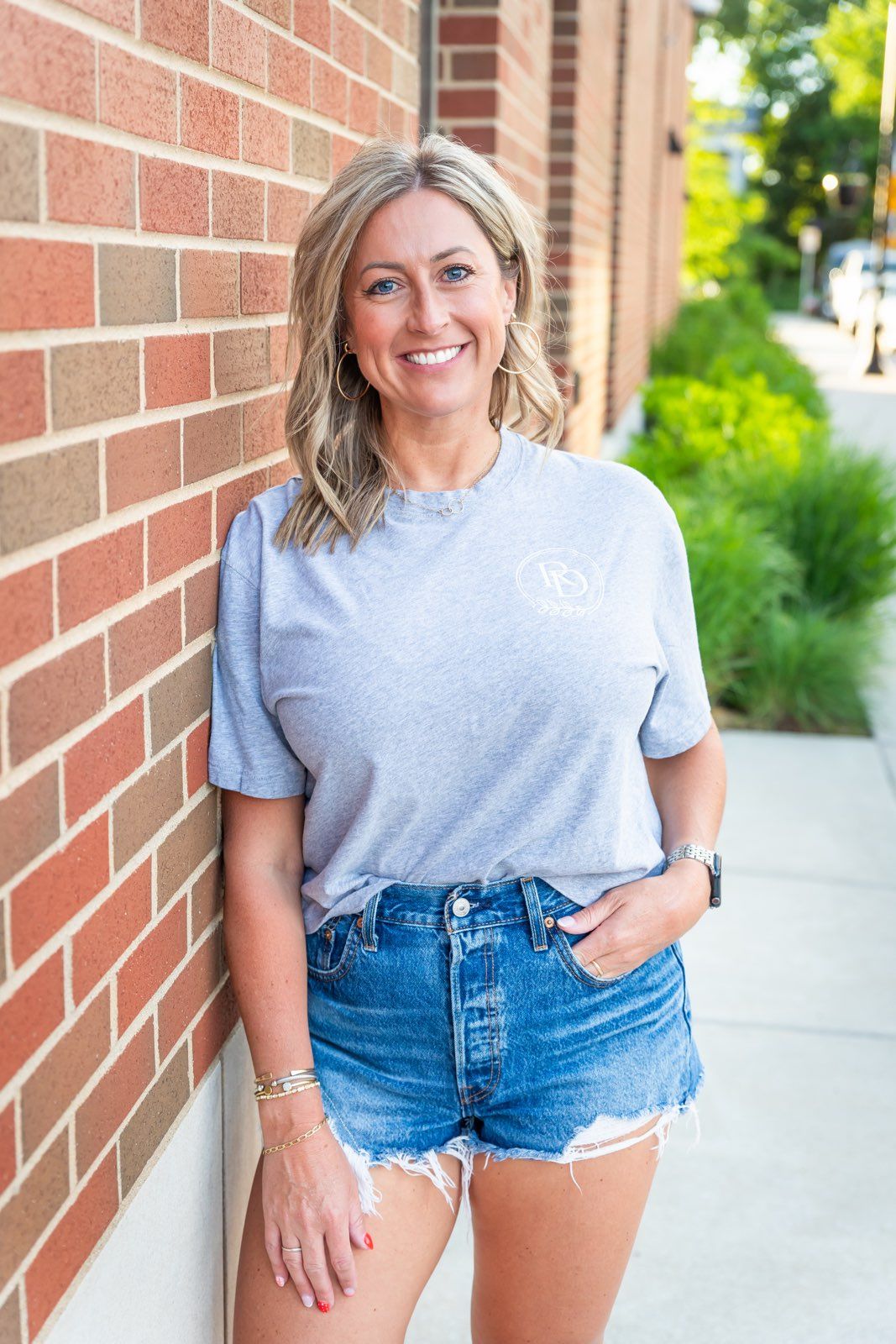 Staci Perkins, founder of Reid Design, smiling outside a brick storefront.