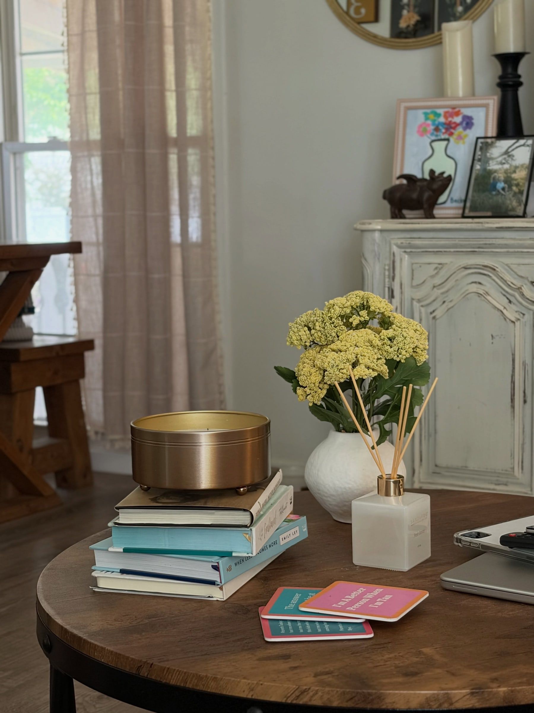 Side table styled with yellow hydrangeas, stacked books and a brass bowl
