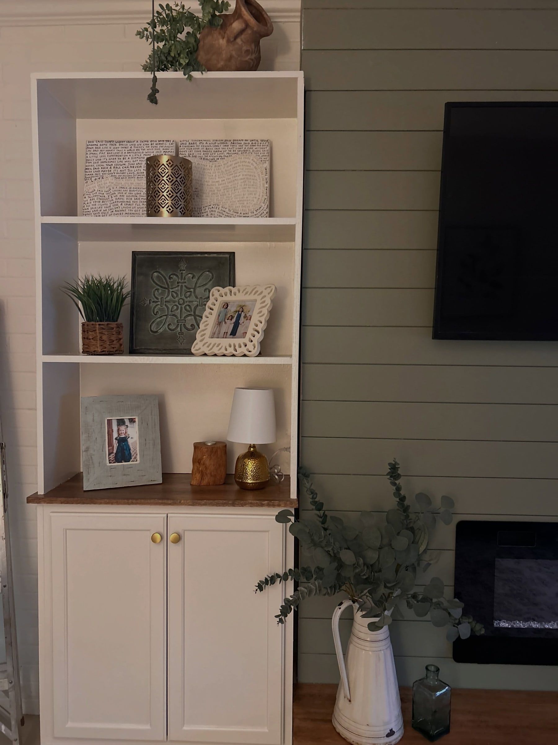 White built-in shelves styled with frames, a lamp and greenery