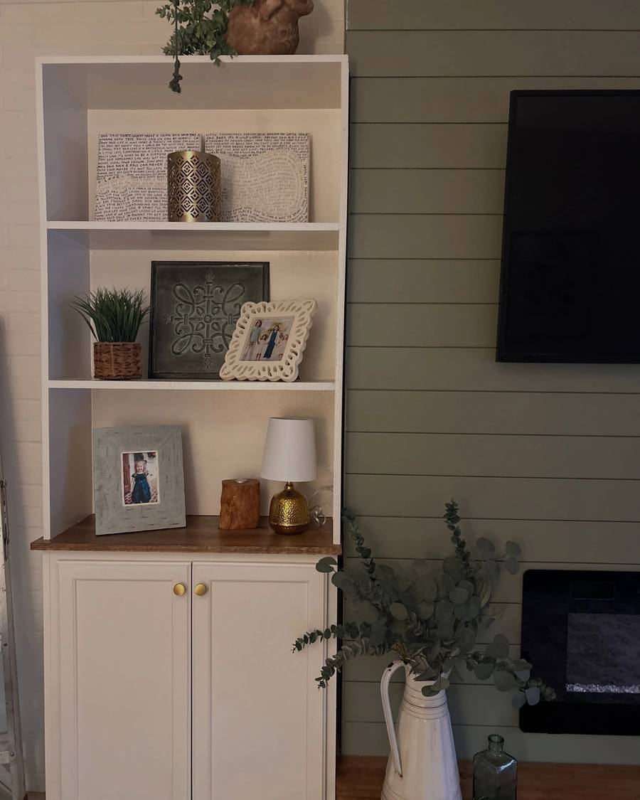 White built-in shelves styled with frames, a lamp and greenery