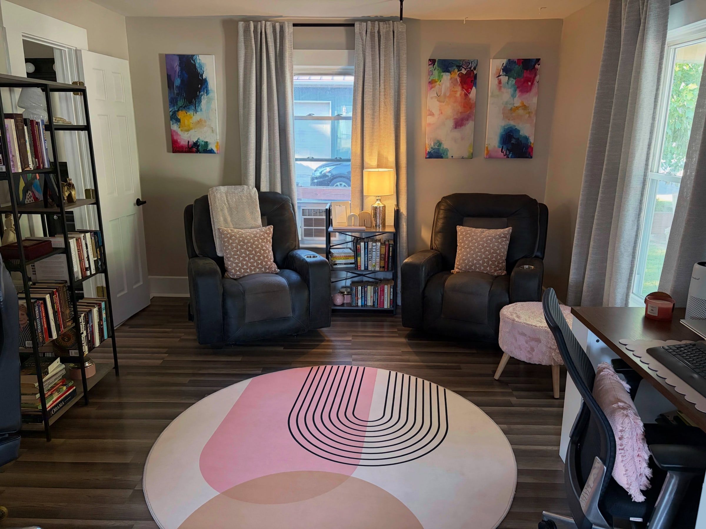 Den in Lebanon, Indiana with two recliners, colourful abstract art and a round pink rug