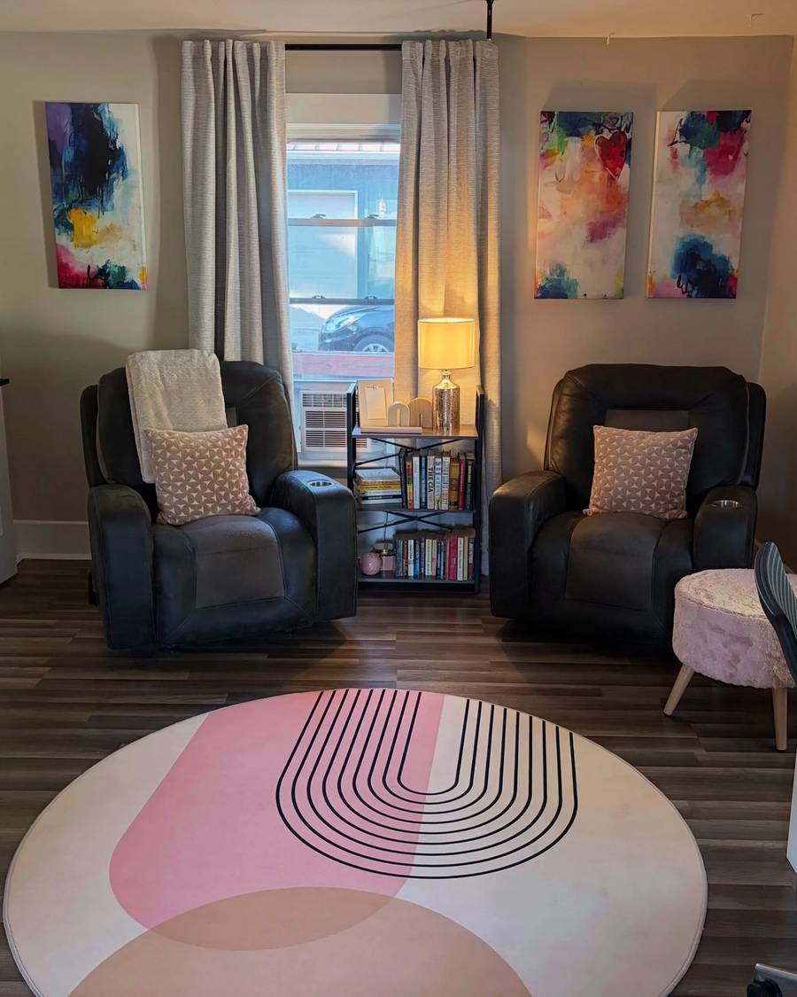 Den in Lebanon, Indiana with two recliners, colourful abstract art and a round pink rug