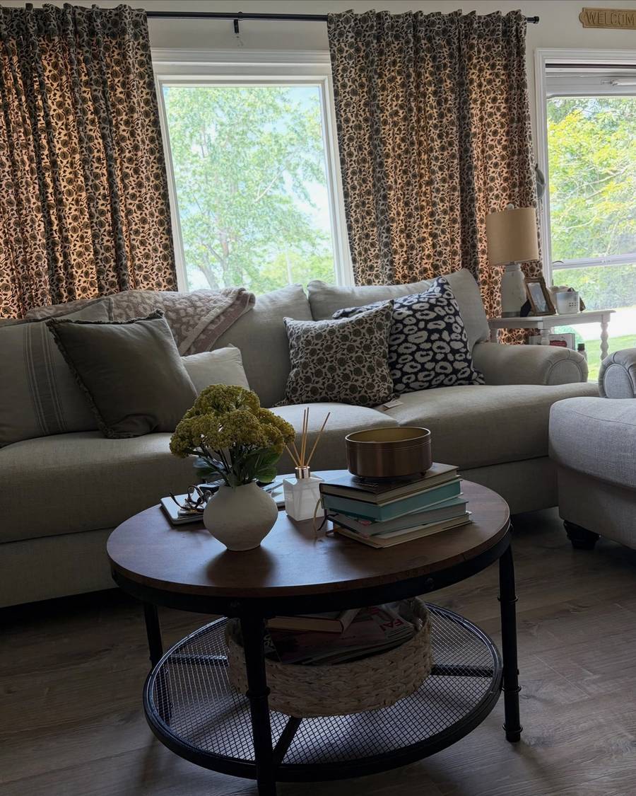 Sunny living room with a grey sectional and a round coffee table styled with books and flowers