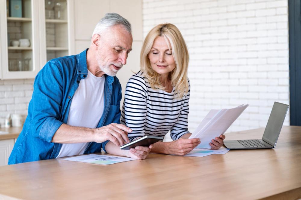 A couple reviewing retirement planning paperwork and financial calculations together.