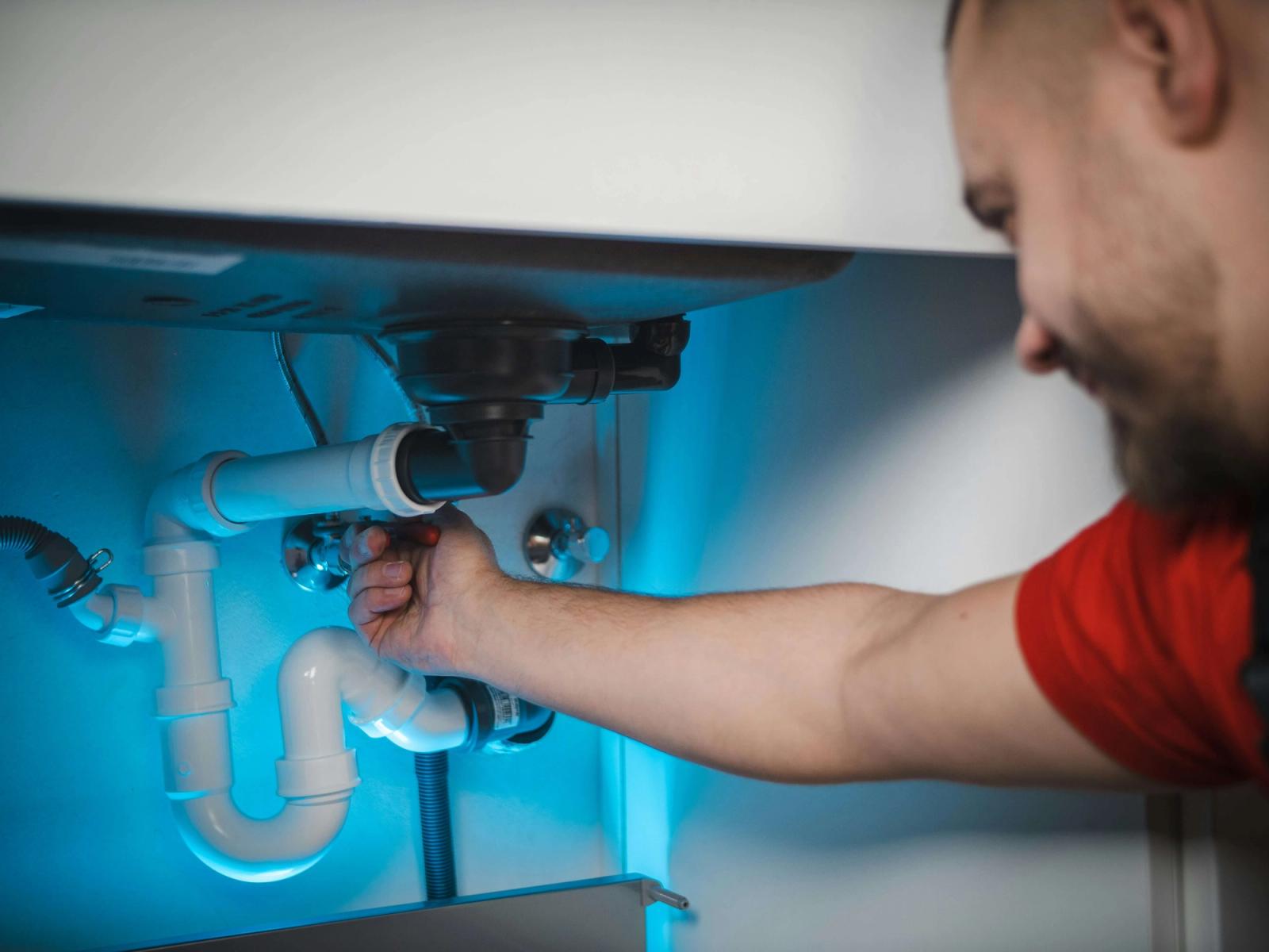 Plumber fixing pipes under the sink
