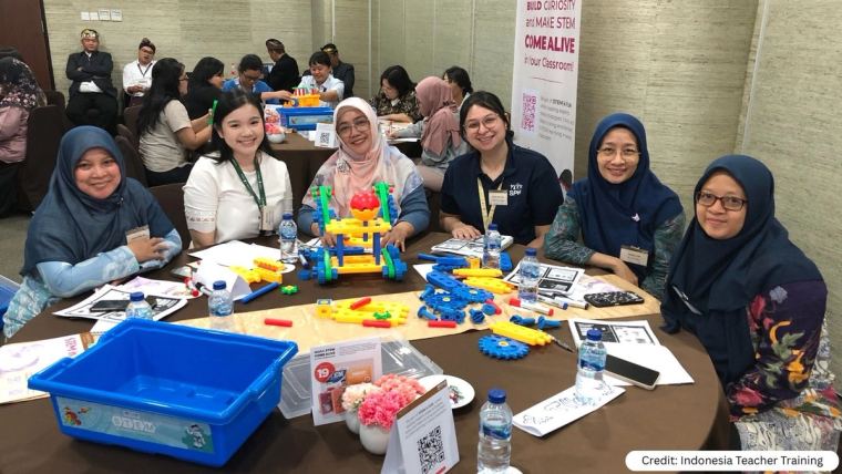 Profesores reunidos en una mesa redonda montando maquetas durante una sesión de formación en Indonesia