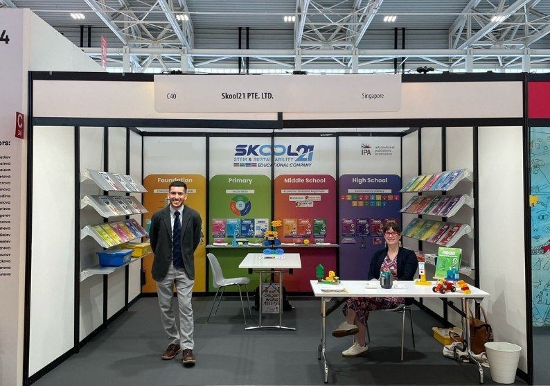 The SKOOL21 stand at an international book fair, with the series arranged by stage and the team at the counter